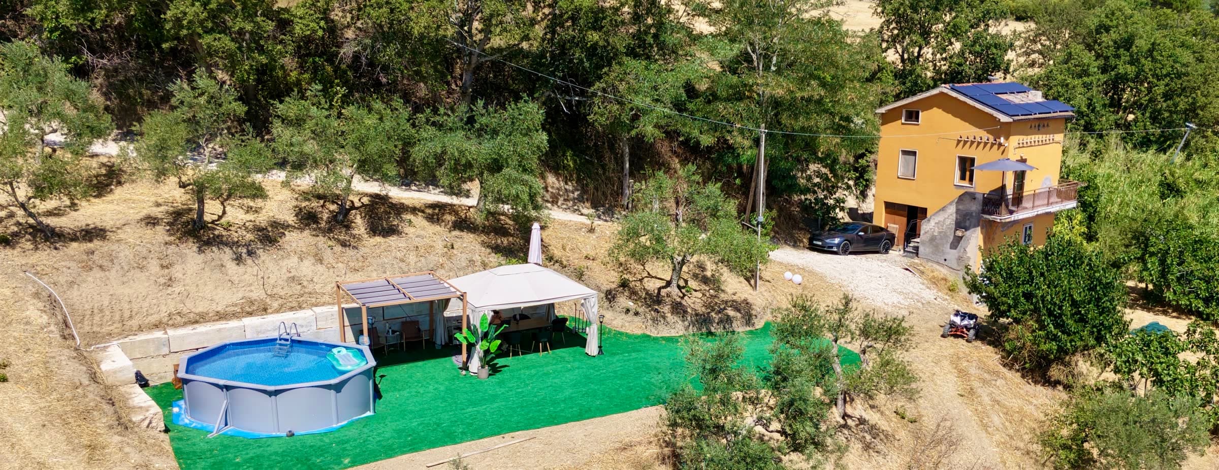 Aerial panorama of Casa del Juniper with solar panels on the roof, the pool and the pergola in the garden